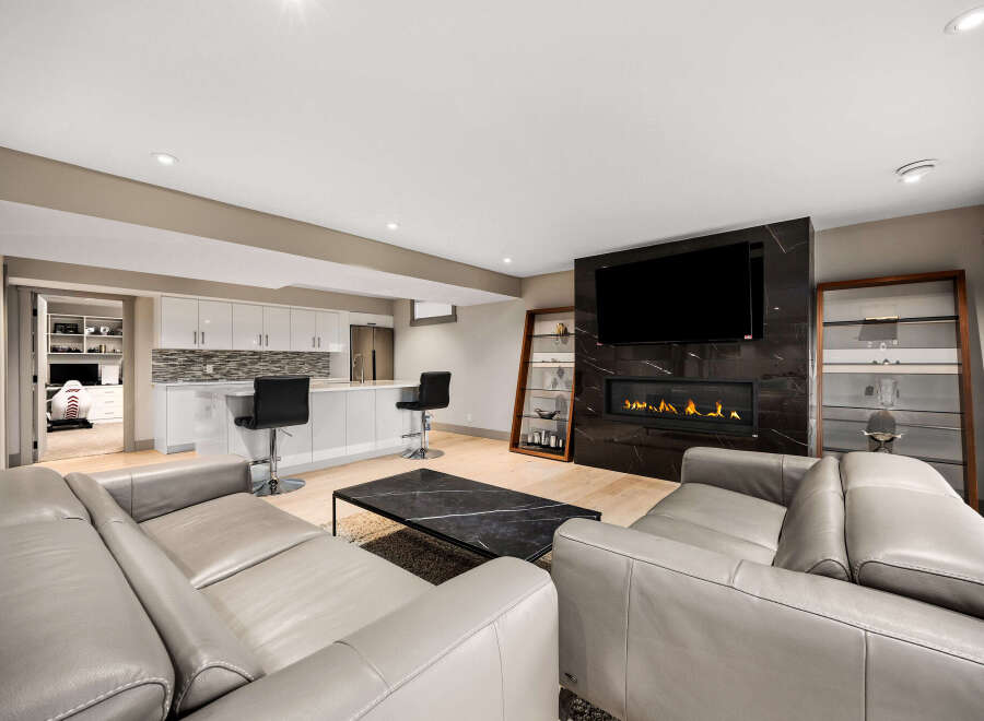 Experience modern luxury in this stunning living space, featuring a sleek gas fireplace set against a dramatic marble accent wall and a large flat-screen TV.