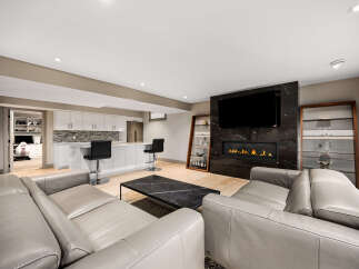 Experience modern luxury in this stunning living space, featuring a sleek gas fireplace set against a dramatic marble accent wall and a large flat-screen TV.