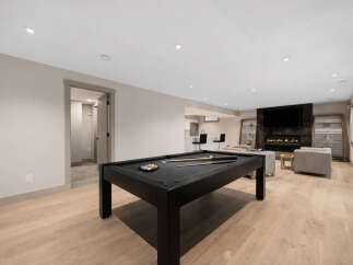 This modern basement features a sleek black pool table as the centerpiece, perfect for entertainment.