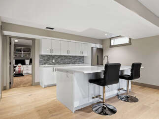 Discover modern living in this stunning basement suite, featuring a sleek, high-gloss white kitchen with a captivating mosaic tile backsplash.
