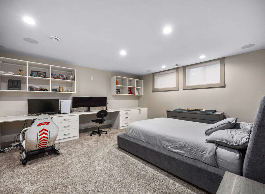 This modern bedroom features a spacious desk area with dual monitors and a gaming chair, perfect for work or play.