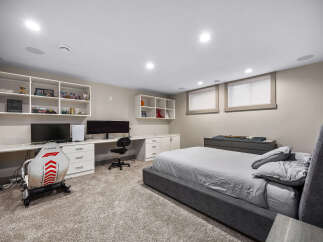This modern bedroom features a spacious desk area with dual monitors and a gaming chair, perfect for work or play.