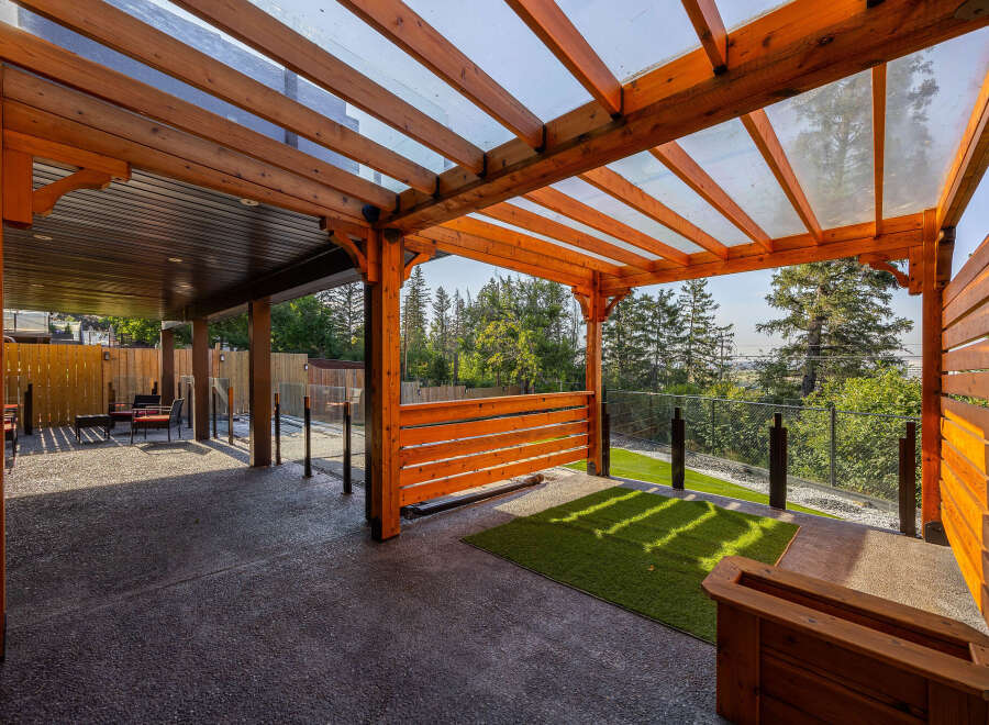 Experience seamless indoor-outdoor living with this stunning covered patio, featuring a modern wooden pergola with a transparent roof.