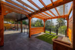 Experience seamless indoor-outdoor living with this stunning covered patio, featuring a modern wooden pergola with a transparent roof.