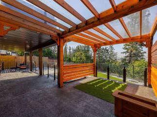 Experience seamless indoor-outdoor living with this stunning covered patio, featuring a modern wooden pergola with a transparent roof.