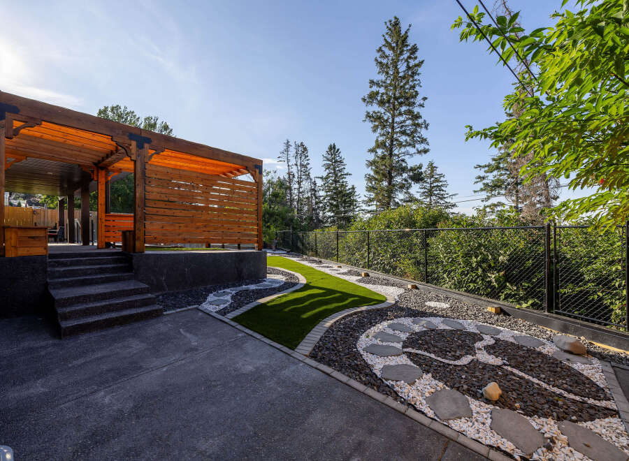 Experience outdoor living at its finest with this beautifully designed backyard featuring a modern wooden pergola and a multi-level patio.