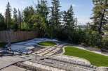 Discover this beautifully landscaped backyard, featuring a modern patio with intricate paving stone patterns and contrasting white and dark gravel accents.