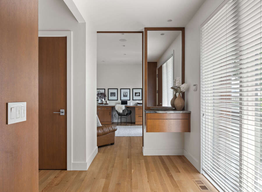 This modern entryway features warm wood tones with a sleek white light switch panel and a matching door.