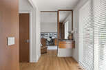This modern entryway features warm wood tones with a sleek white light switch panel and a matching door.