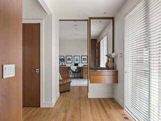 This modern entryway features warm wood tones with a sleek white light switch panel and a matching door.