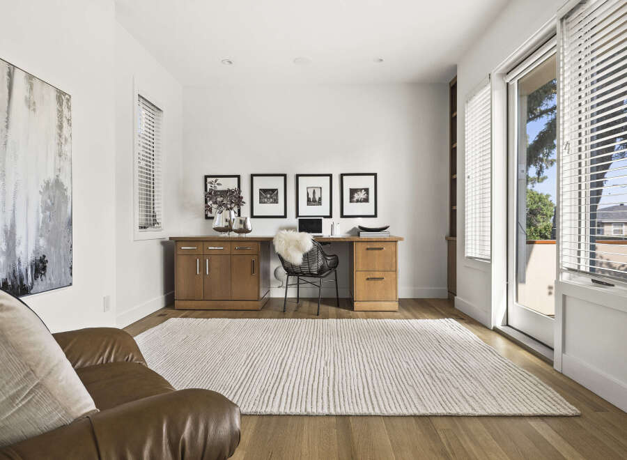 This home office features a modern aesthetic with a sleek wooden desk and a comfortable leather armchair.