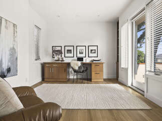 This home office features a modern aesthetic with a sleek wooden desk and a comfortable leather armchair.