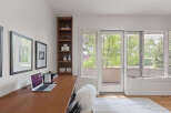This home office features a sleek wooden desk with a laptop and a fluffy white chair, perfect for productive work sessions.