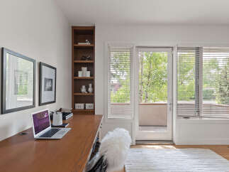This home office features a sleek wooden desk with a laptop and a fluffy white chair, perfect for productive work sessions.