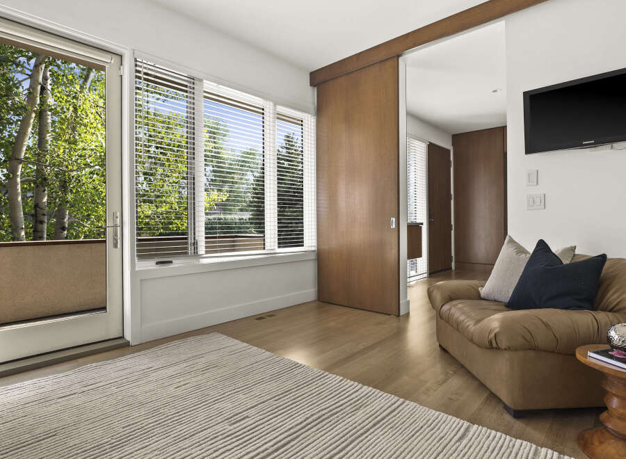 Experience natural light and serene views from this inviting living space, featuring large windows and a glass door that opens to lush greenery.