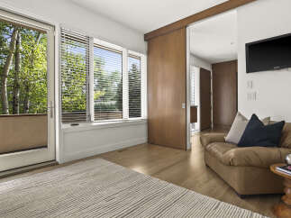 Experience natural light and serene views from this inviting living space, featuring large windows and a glass door that opens to lush greenery.