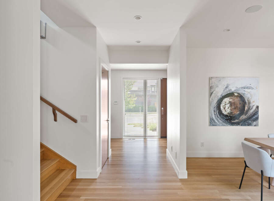 Step into this bright and airy hallway, featuring a modern wooden staircase and a sleek handrail.
