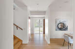 Step into this bright and airy hallway, featuring a modern wooden staircase and a sleek handrail.