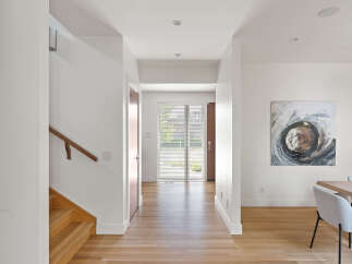 Step into this bright and airy hallway, featuring a modern wooden staircase and a sleek handrail.