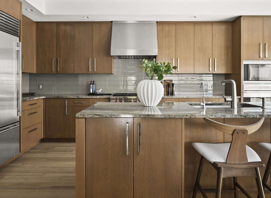 Experience luxury in this modern kitchen featuring sleek, custom wood cabinetry and a stunning granite island.
