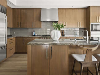 Experience luxury in this modern kitchen featuring sleek, custom wood cabinetry and a stunning granite island.