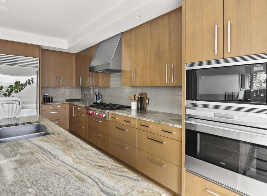Experience culinary excellence in this stunning modern kitchen, featuring sleek, warm wood cabinetry and a professional-grade Wolf range.