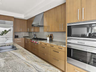 Experience culinary excellence in this stunning modern kitchen, featuring sleek, warm wood cabinetry and a professional-grade Wolf range.