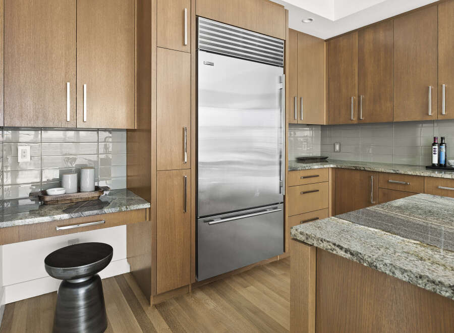 Experience modern luxury in this stunning kitchen, featuring sleek, custom wood cabinetry and a professional-grade stainless steel refrigerator.