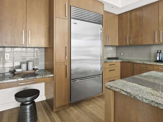 Experience modern luxury in this stunning kitchen, featuring sleek, custom wood cabinetry and a professional-grade stainless steel refrigerator.