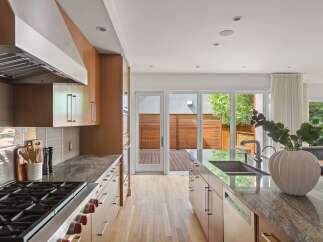 Experience modern living in this stunning kitchen featuring sleek, custom wood cabinetry and luxurious granite countertops.