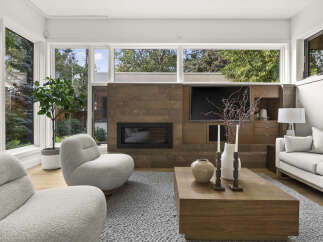 Experience modern living in this stunning living room, featuring a sleek fireplace with a stone accent wall and a built-in entertainment center.