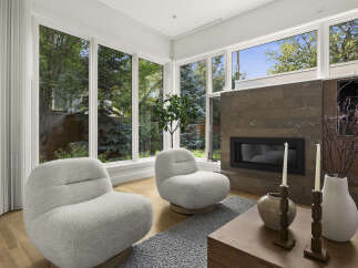 Experience modern living in this stunning living room, featuring a sleek fireplace and large windows that flood the space with natural light.