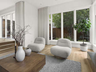 Experience modern living in this bright and airy living space, featuring plush boucle armchairs perfect for relaxation.