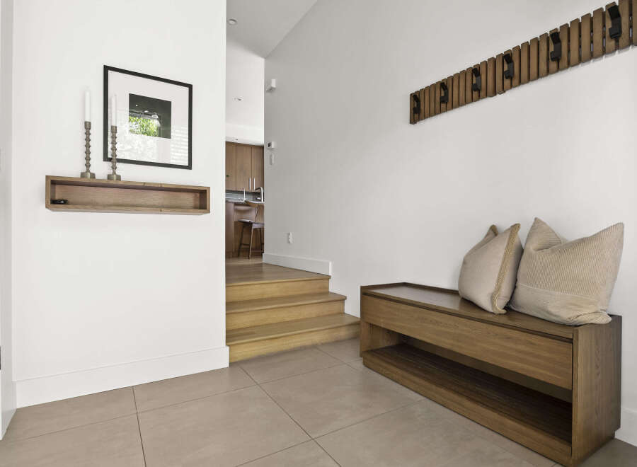 Welcome guests into this stylish entryway featuring a modern wooden bench with plush cushions, perfect for removing shoes.