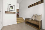 Welcome guests into this stylish entryway featuring a modern wooden bench with plush cushions, perfect for removing shoes.