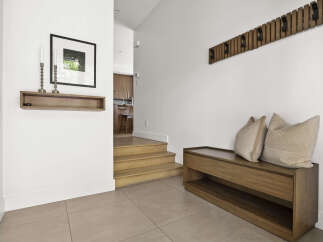 Welcome guests into this stylish entryway featuring a modern wooden bench with plush cushions, perfect for removing shoes.