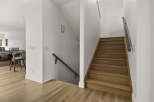 Step into this beautifully designed home featuring a modern staircase with warm wood treads and a sleek railing.