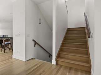 Step into this beautifully designed home featuring a modern staircase with warm wood treads and a sleek railing.