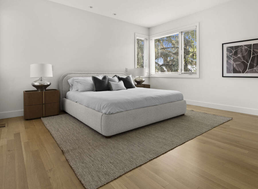 Experience modern comfort in this serene bedroom, featuring a plush, upholstered bed as the centerpiece.