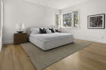 Experience modern comfort in this serene bedroom, featuring a plush, upholstered bed as the centerpiece.