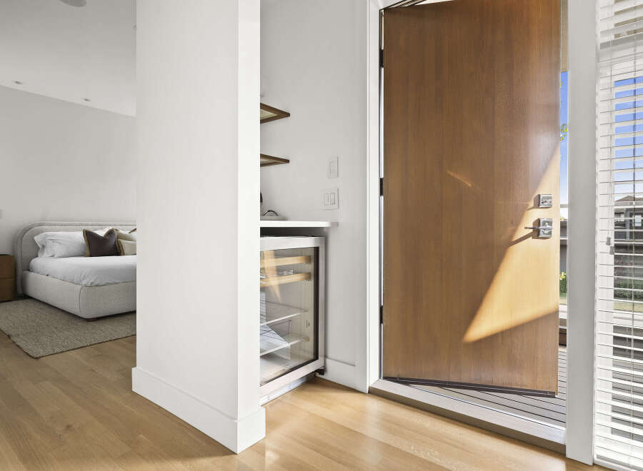 Step into this inviting entryway featuring a sleek wine fridge and a glimpse into a serene bedroom with a plush bed.