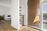 Step into this inviting entryway featuring a sleek wine fridge and a glimpse into a serene bedroom with a plush bed.