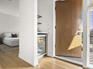 Step into this inviting entryway featuring a sleek wine fridge and a glimpse into a serene bedroom with a plush bed.