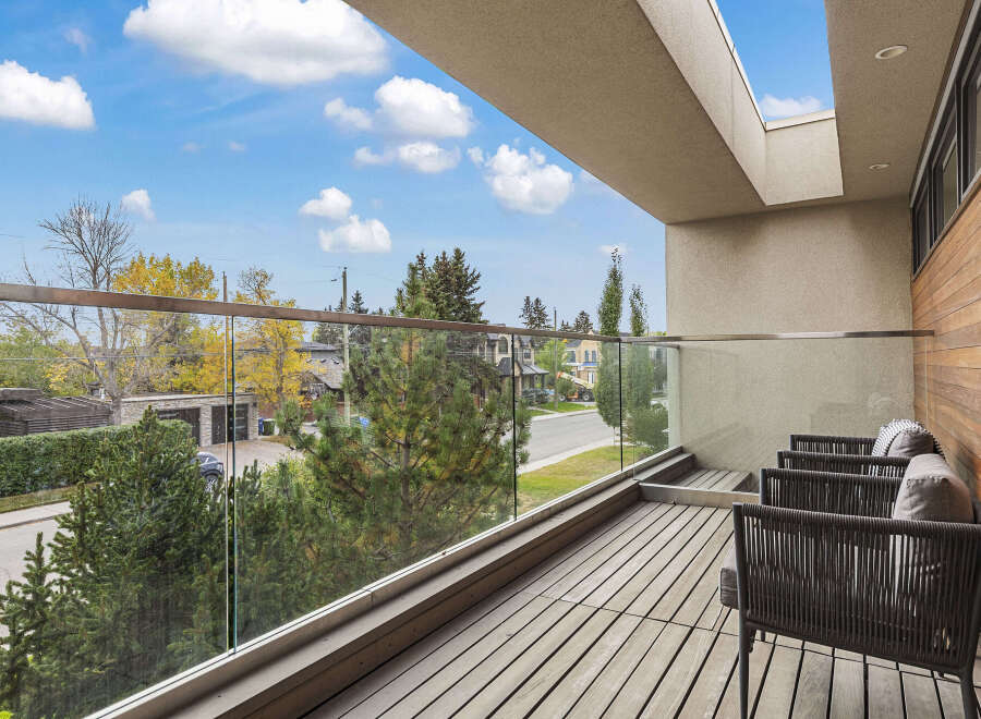 Enjoy breathtaking views from this modern balcony, featuring a sleek glass railing and comfortable outdoor seating.