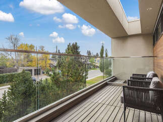 Enjoy breathtaking views from this modern balcony, featuring a sleek glass railing and comfortable outdoor seating.