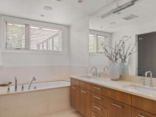 Experience luxury in this spacious bathroom featuring a deep soaking tub and a dual vanity with ample counter space.