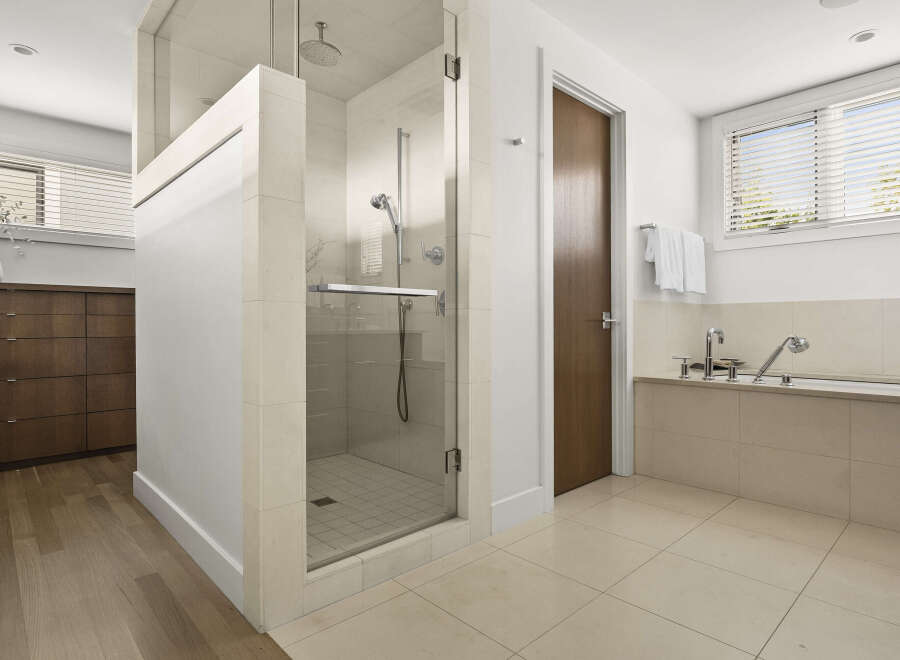 Experience luxury in this modern bathroom featuring a spacious glass-enclosed shower with a rainfall showerhead and a deep soaking tub.