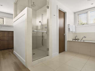 Experience luxury in this modern bathroom featuring a spacious glass-enclosed shower with a rainfall showerhead and a deep soaking tub.