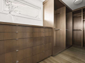 Discover ample storage solutions in this modern walk-in closet, featuring a sleek dresser with multiple drawers and built-in shelving with hanging rods.