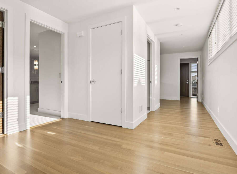 Step into this bright and airy hallway, featuring gleaming hardwood floors that reflect the natural light streaming through the blinds.